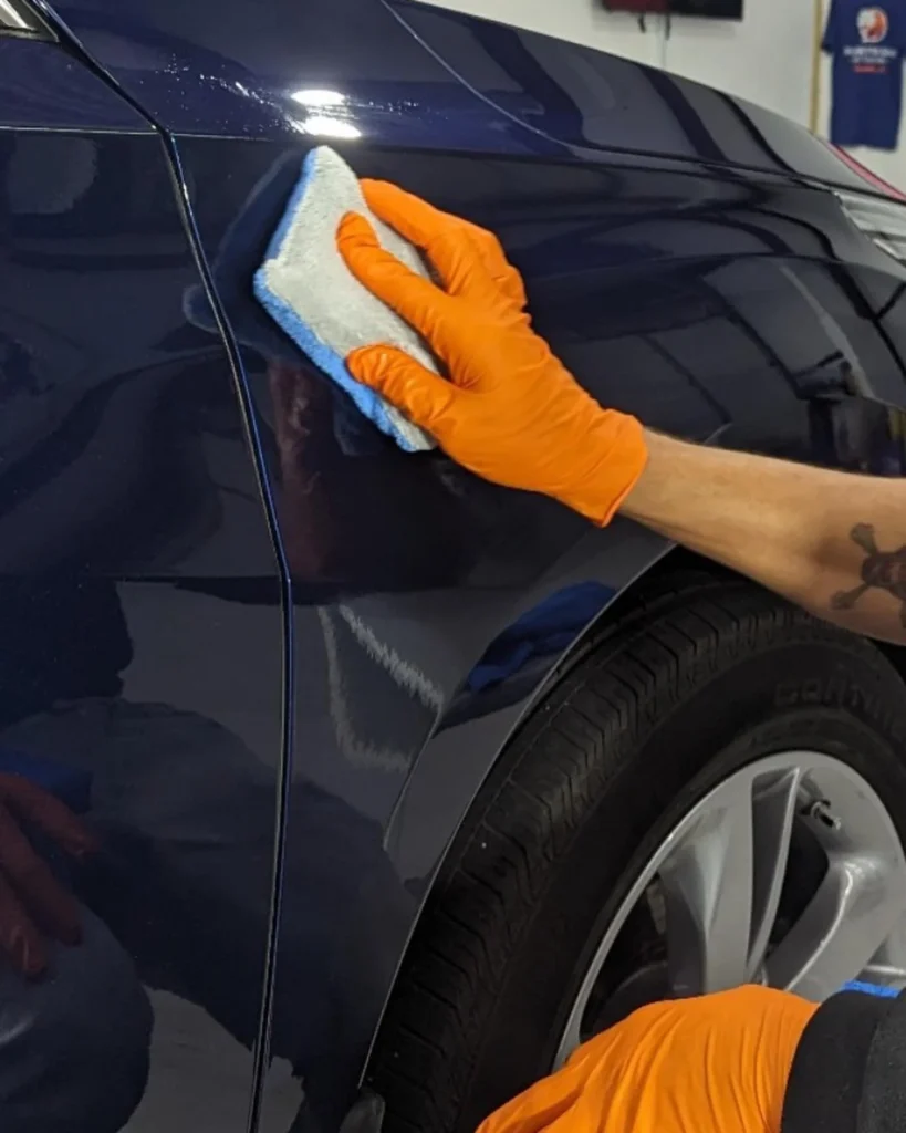 Technician applying System X ceramic coating to a dark blue vehicle panel in Spartanburg SC
