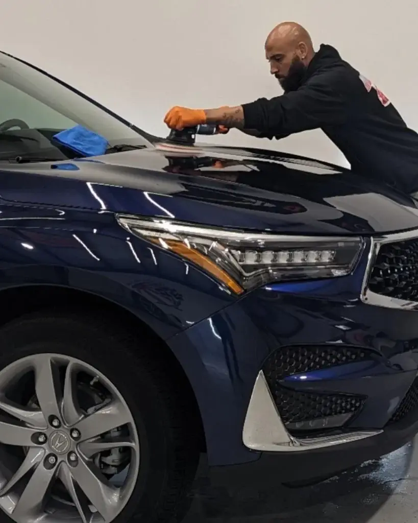 Machine polishing the hood of a dark blue SUV during paint correction in Spartanburg SC